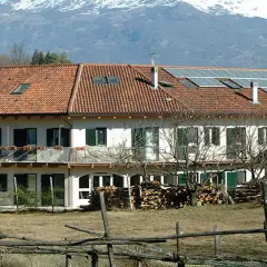 Edificio con pannelli solari, forse parte della comunità Damanhur, con montagne innevate sullo sfondo.