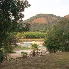 Un angolo di pace ad Agnano, dove si trova un complesso con piscine e vegetazione lussureggiante, incorniciato da colline verdi.