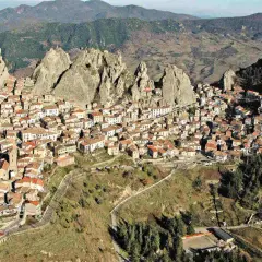 Un pittoresco borgo in Basilicata, aggrappato a rocce imponenti, con case dai tetti rossi che si estendono sul pendio.