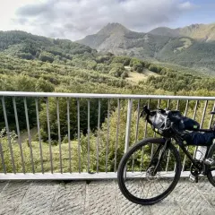 Bicicletta da cicloturismo pronta per esplorare l'Appennino Tosco Emiliano, con un panorama mozzafiato di boschi e montagne.