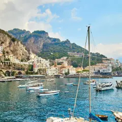 Un incantevole mare a Napoli, con un borgo colorato aggrappato alla scogliera e barche che ondeggiano nell'acqua cristallina.