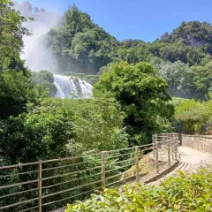Sentiero panoramico nella Valnerina con la cascata che si intravede tra il verde lussureggiante.