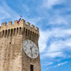 Torre dell'orologio a Gualtieri, con bandiera tricolore e cielo azzurro.