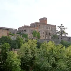 Castello medievale su una collina, circondato da alberi verdi. Un esempio dei suggestivi borghi vicino Parma.