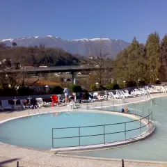 Piscine termali con lettini e ombrelloni, montagne innevate sullo sfondo. Un'oasi di relax per godersi le contursi terme gratis.