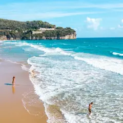 Spiaggia dorata con onde azzurre, scogliere verdi e un castello in cima. Perfetto per chi cerca il mare nel Lazio dove andare.
