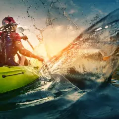 Persona in kayak crea un'onda spettacolare, un'immagine perfetta per le vacanze sportive.