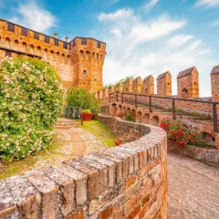 Un sentiero tra rose e mattoni rossi porta verso un castello, un assaggio dei 5 borghi più belli delle Marche.