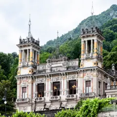 Edificio storico con torri e decorazioni elaborate, immerso nel verde delle montagne. Un luogo incantevole per una **spa San Pellegrino**.