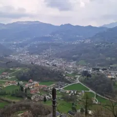 Panoramica della valle Imagna con case sparse tra colline verdi e montagne nebbiose sullo sfondo.