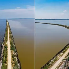 La ciclabile degli angeli, un sentiero che divide acque limpide e torbide, si estende all'infinito sotto un cielo azzurro.