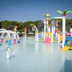 Area giochi acquatica colorata con scivoli e spruzzi d'acqua, perfetta per divertirsi alle terme Lignano.