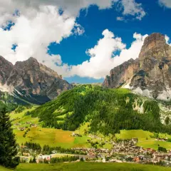 Un villaggio alpino incastonato tra imponenti vette rocciose e verdi pascoli. Una splendida località di montagna.