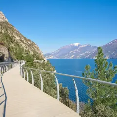 Una moderna ciclabile a picco sul lago, con montagne sullo sfondo. Potrebbe essere la ciclabile più bella d'Italia.