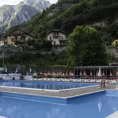 Piscine azzurre a Sant'Omobono Terme, con montagne verdi sullo sfondo e case arroccate.