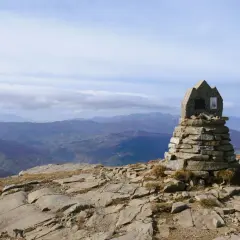 Cairn in pietra sulla cima del monte più alto Emilia Romagna, con vista panoramica sulle colline sottostanti.