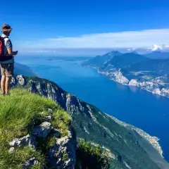 Escursionista ammira il panorama mozzafiato dal Monte Baldo. Cosa vedere: il lago blu intenso e le montagne verdi.