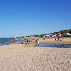 Gente rilassata sulle bellissime spiagge di Termoli, con il mare azzurro e la costa verdeggiante sullo sfondo.