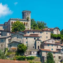 Antico borgo arroccato tra le colline dell'Appennino Tosco Emiliano, con case in pietra e una torre medievale.