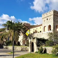 Antico palazzo con torri merlate, palme e un giallo vessillo, incantevole scenario per le terme naturali Cilento.
