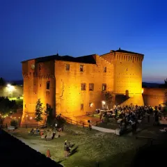 Rocca Malatestiana illuminata di sera, con persone che socializzano e godono dell'atmosfera. Un luogo suggestivo da scoprire tra le cose da vedere a Cesena.