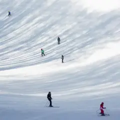 Sciare nel Lazio: persone godono della neve su una pista, con ombre suggestive degli alberi.