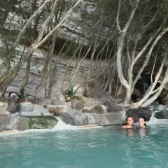Due bambine si godono le terme libere di Ischia, immerse in acque turchesi tra rocce e vegetazione rigogliosa.