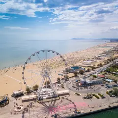 Ruota panoramica su una delle spiagge più belle dell'Emilia Romagna, con ombrelloni dorati e mare azzurro.
