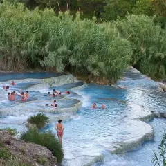 Persone si rilassano nelle cascate termali naturali. Un luogo ideale per scoprire le terme Pavia prezzi.
