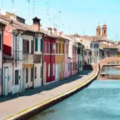 Comacchio: case colorate lungo il canale, un ponte ad arco e torri. Ideale per scoprire cosa vedere a Comacchio e dintorni in due giorni.