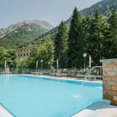 Piscina con acqua azzurra e montagne verdi sullo sfondo, un'oasi di relax alle terme di Valdieri.