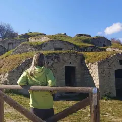 Pietragalla cosa vedere: antiche case-grotta scavate nella collina, con una donna che le osserva. Un luogo suggestivo da esplorare.