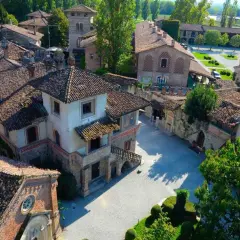 Un borgo fiabesco vicino Piacenza, con tetti in cotto e torri medievali, immerso nel verde.