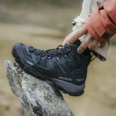 Come scegliere scarpe da trekking: un piede indossa uno scarpone nero Mammut su una roccia.