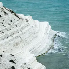 La scogliera bianca di Sicilia, con le sue stratificazioni calcaree, si tuffa nel mare turchese.