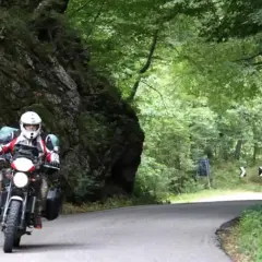 Motociclista in un percorso tortuoso tra rocce e alberi. Un'avventura di giri in moto in Emilia Romagna.