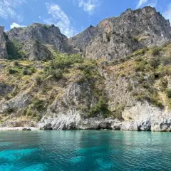 Paesaggi mozzafiato mare: scogliere rocciose ricoperte di vegetazione si tuffano in acque cristalline e turchesi.