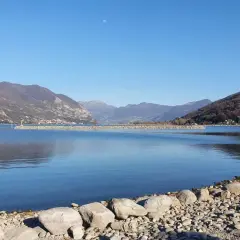 Calm lake with mountains in the background and a rocky shore in the foreground.