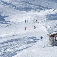 Sciare in un paesaggio innevato, perfetto per una settimana bianca in Piemonte. Piccola baita di pietra sulla pista.