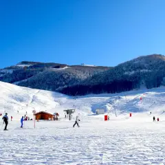 Piste innevate e sciatori in azione, un perfetto esempio di dove si scia in Abruzzo. Montagne innevate e cielo azzurro.