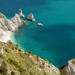 Scogliere bianche e mare turchese in una splendida località sulla riviera del Conero. Una piccola spiaggia nascosta e faraglioni emergono dall'acqua cristallina.