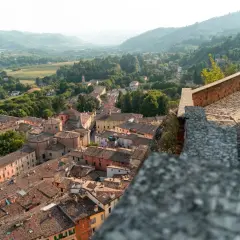 Panoramica di **borghi vicino Reggio Emilia** con tetti in cotto e colline verdi sullo sfondo.