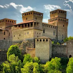 Roccastraordinaria di Torrechiara, un gioiello incastonato tra le colline di Parma, Emilia Romagna, con torri imponenti e un cielo drammatico.