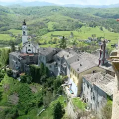 Un borgo incantevole con un campanile bianco, tetti in pietra e colline verdi. Un luogo dove compiano cosa vedere, tra storia e natura.