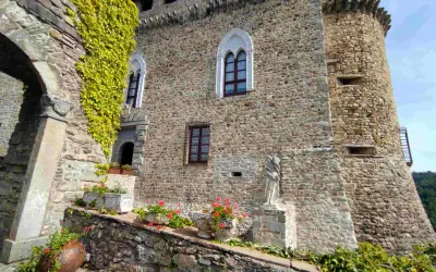 Antica dimora a Compiano, Parma, con mura in pietra, edera rampicante, fiori e una statua.