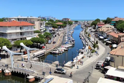 Un canale navigabile a Cervia, dove si trova un vivace porto turistico con barche a vela ormeggiate e case colorate lungo le rive.