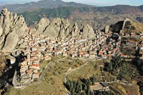 Un pittoresco borgo in Basilicata, aggrappato a rocce imponenti, con case dai tetti rossi che si estendono sul pendio.