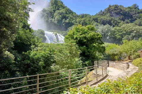 Sentiero panoramico nella Valnerina con la cascata che si intravede tra il verde lussureggiante.
