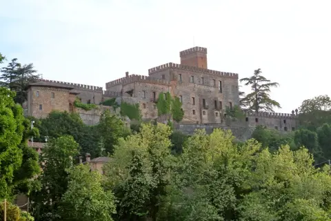Castello medievale su una collina, circondato da alberi verdi. Un esempio dei suggestivi borghi vicino Parma.