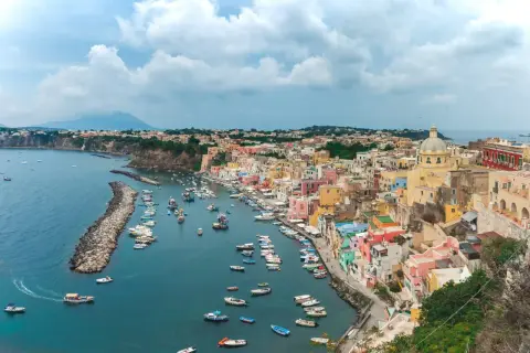 Un pittoresco borgo colorato sul mare vicino Napoli, con barche ormeggiate in un porto tranquillo e una vista mozzafiato.